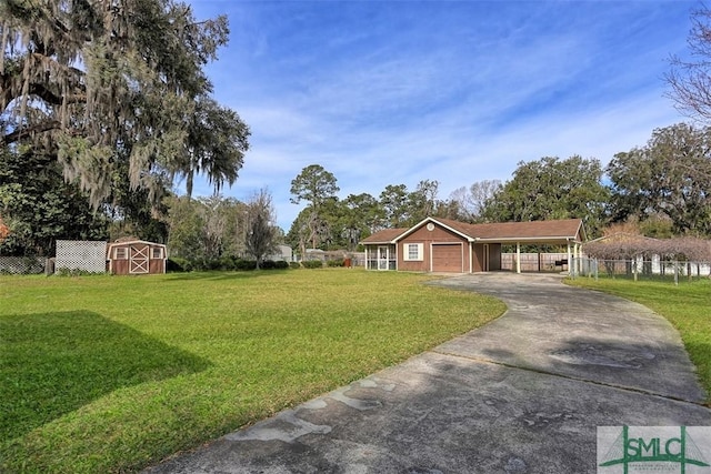 view of yard featuring an outbuilding, a garage, fence, a carport, and driveway