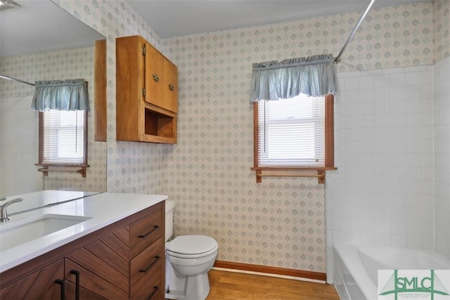 bathroom featuring vanity, wood finished floors, toilet, and wallpapered walls