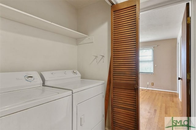 laundry area with baseboards, laundry area, light wood finished floors, and washer and dryer