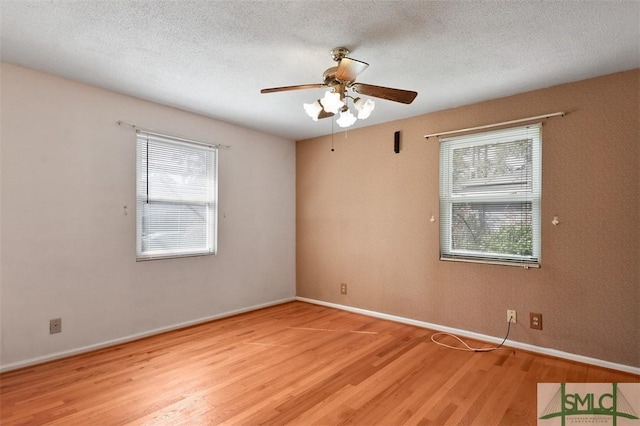 empty room featuring baseboards, ceiling fan, light wood-style flooring, and a textured ceiling