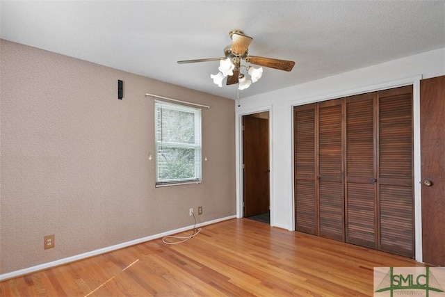 unfurnished bedroom with light wood-type flooring, a ceiling fan, baseboards, and a closet