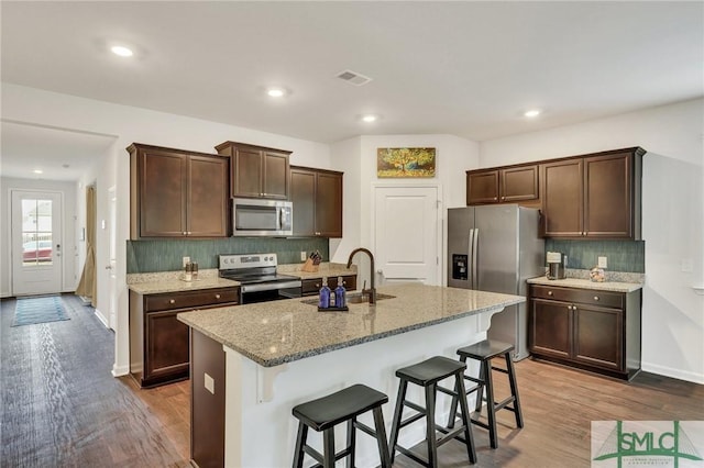 kitchen featuring decorative backsplash, stainless steel appliances, a sink, and wood finished floors