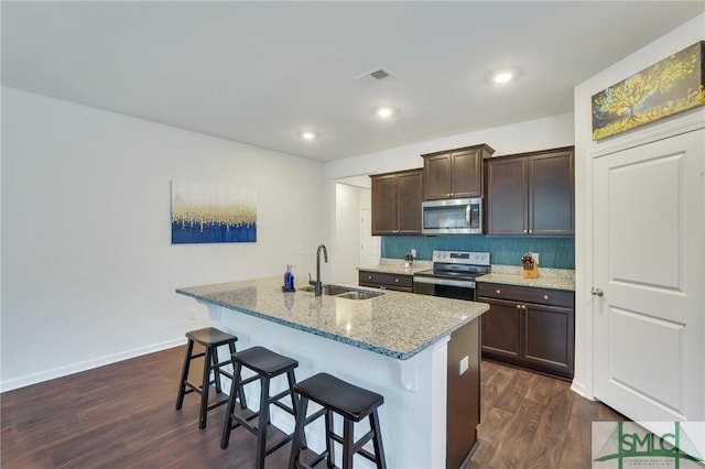 kitchen featuring dark wood finished floors, a breakfast bar area, visible vents, appliances with stainless steel finishes, and a sink