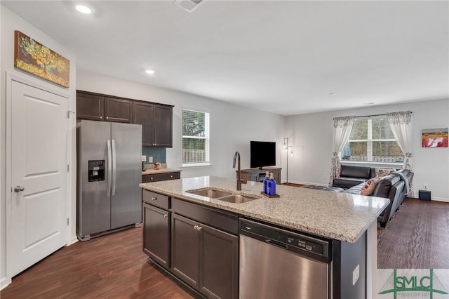 kitchen featuring open floor plan, stainless steel appliances, dark wood-style flooring, and a sink