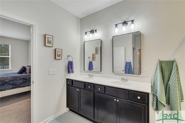 bathroom with double vanity, a sink, baseboards, and ensuite bathroom