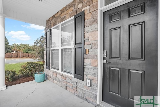 entrance to property featuring covered porch and stone siding