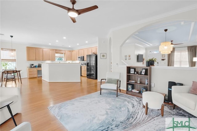 living room featuring light wood-style floors, arched walkways, and a wealth of natural light