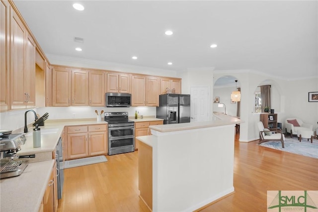 kitchen featuring stainless steel appliances, arched walkways, light wood-type flooring, and light brown cabinetry