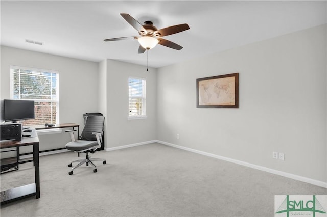 carpeted home office with a ceiling fan, visible vents, and baseboards