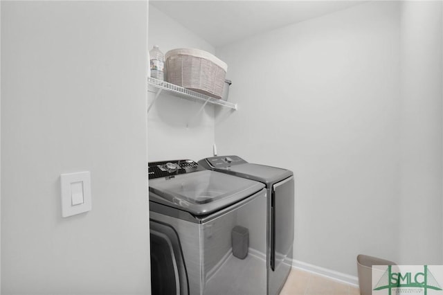 laundry room featuring washing machine and dryer, laundry area, light tile patterned flooring, and baseboards