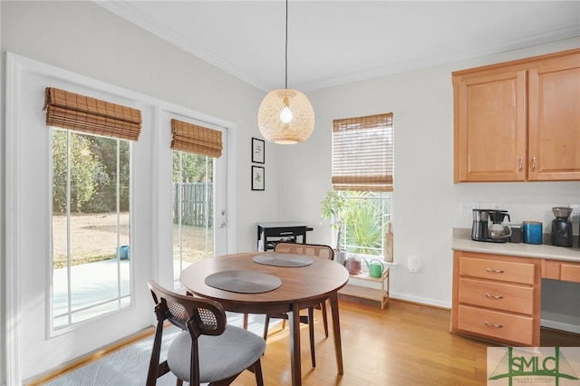 dining space with light wood finished floors, baseboards, ornamental molding, and a wealth of natural light