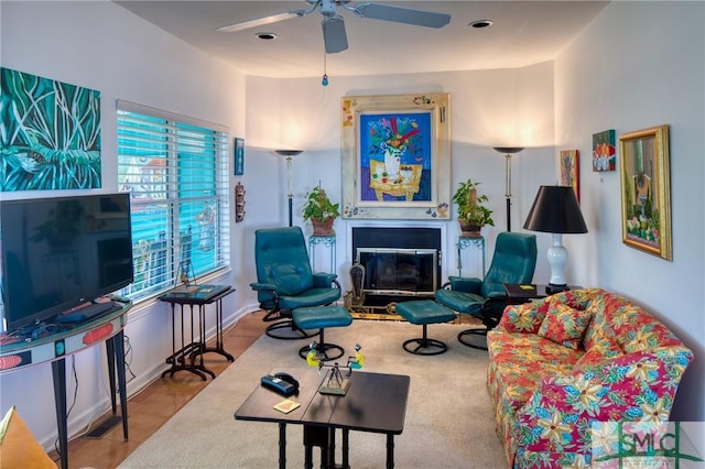 living room with ceiling fan and a glass covered fireplace