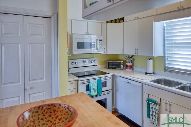 kitchen featuring a toaster, white cabinetry, a sink, butcher block countertops, and white appliances