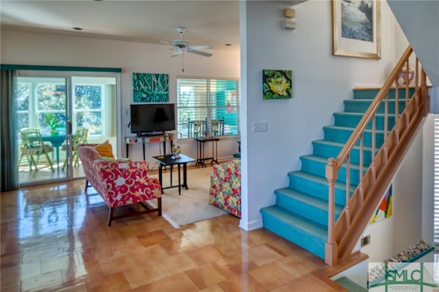 living area featuring ceiling fan, stairway, and a wealth of natural light