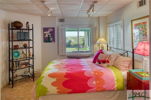 tiled bedroom featuring rail lighting, visible vents, and a drop ceiling