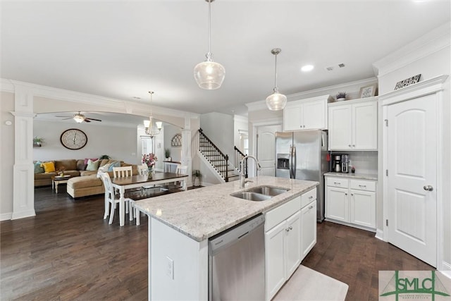 kitchen featuring stainless steel appliances, visible vents, ornamental molding, open floor plan, and a sink