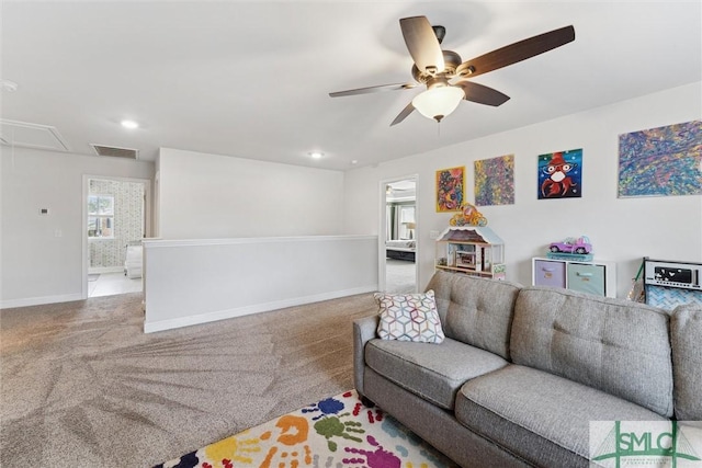 living room with attic access, visible vents, baseboards, a ceiling fan, and carpet floors