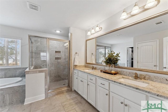 bathroom featuring a stall shower, a sink, visible vents, and a healthy amount of sunlight