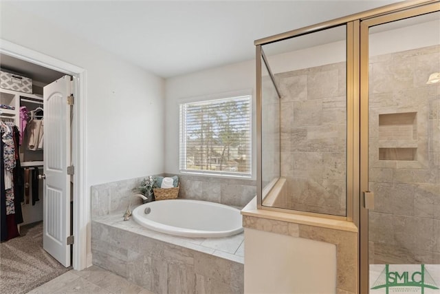 full bathroom featuring a stall shower, a walk in closet, and a garden tub