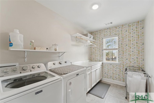 laundry area with light tile patterned floors, cabinet space, visible vents, independent washer and dryer, and baseboards