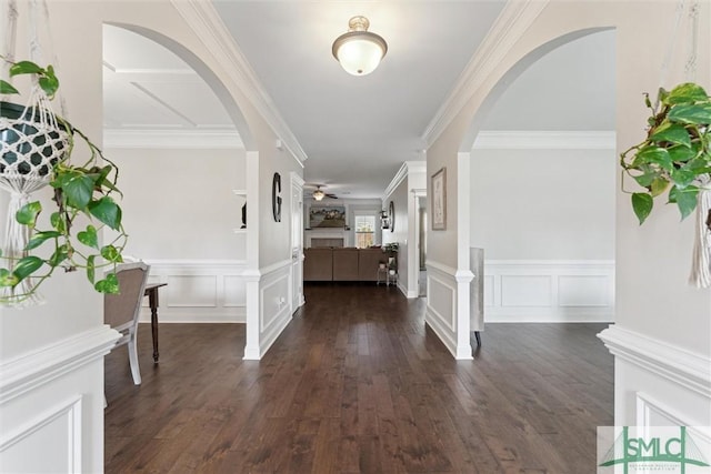 foyer entrance with ceiling fan, arched walkways, a decorative wall, and dark wood-type flooring