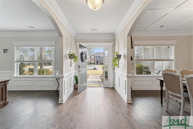 foyer entrance with dark wood-style floors, visible vents, arched walkways, and ornamental molding