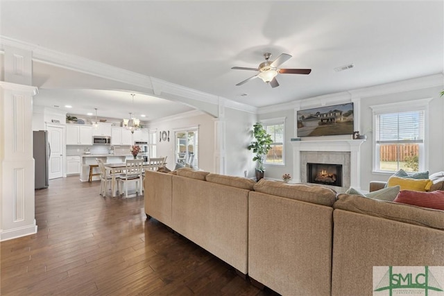 living room featuring dark wood-style floors, crown molding, visible vents, and a healthy amount of sunlight