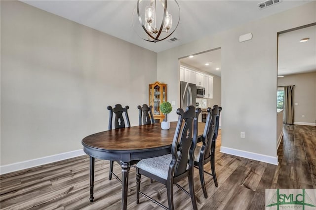 dining area with baseboards, visible vents, a chandelier, and wood finished floors