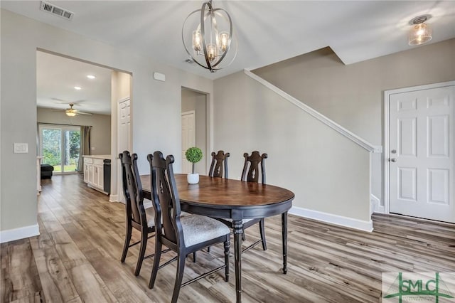 dining room with baseboards, visible vents, wood finished floors, and ceiling fan with notable chandelier