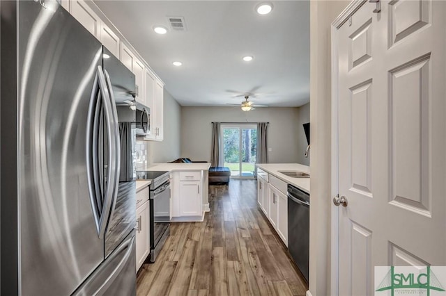 kitchen with light wood-style flooring, appliances with stainless steel finishes, white cabinets, and a sink