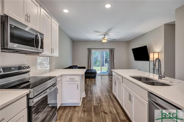 kitchen featuring stainless steel appliances, light countertops, light wood-style flooring, decorative backsplash, and a sink