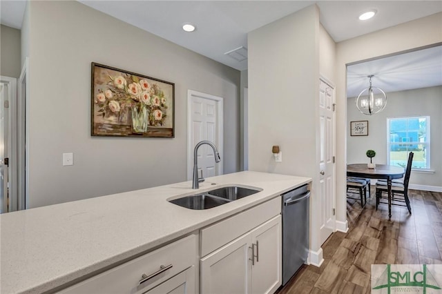 kitchen with dark wood finished floors, white cabinets, a sink, a notable chandelier, and stainless steel dishwasher