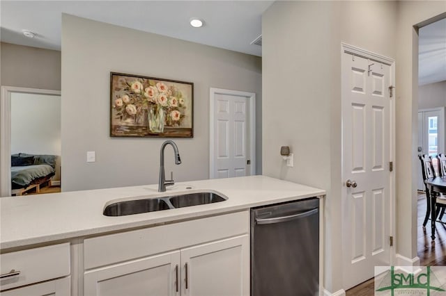 kitchen featuring dishwasher, light countertops, a sink, and white cabinetry