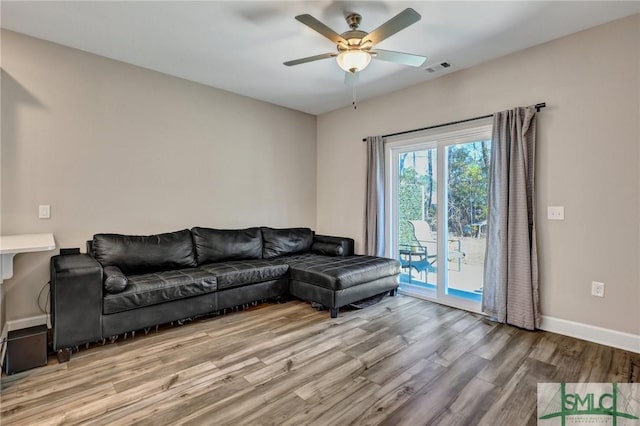 living room with ceiling fan, baseboards, and wood finished floors