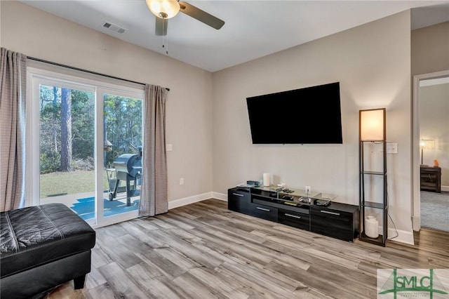 living room featuring baseboards, ceiling fan, visible vents, and light wood-style floors