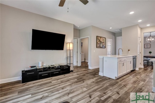 living room featuring ceiling fan with notable chandelier, recessed lighting, light wood-type flooring, and baseboards