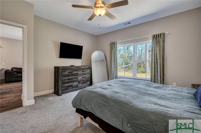 carpeted bedroom featuring a ceiling fan, visible vents, and baseboards