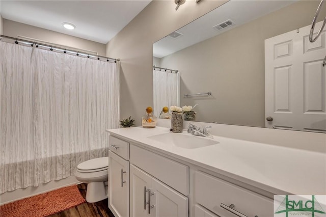 full bathroom featuring toilet, wood finished floors, vanity, visible vents, and shower / bathtub combination with curtain