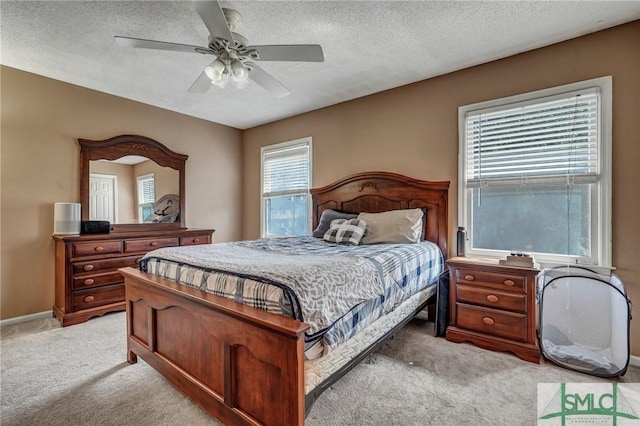 bedroom with ceiling fan, baseboards, a textured ceiling, and light colored carpet