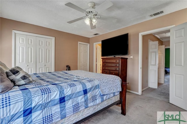 bedroom with two closets, light colored carpet, visible vents, and attic access