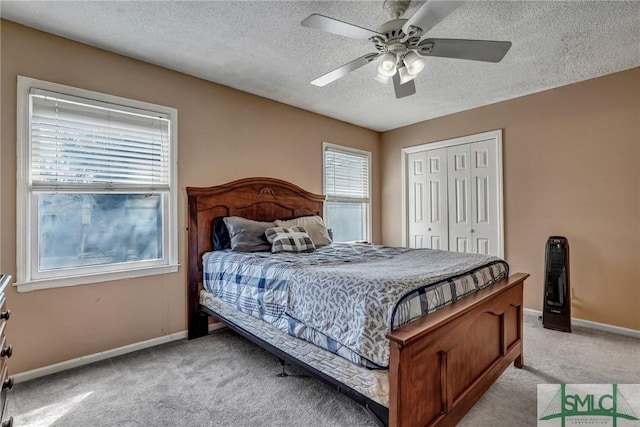 bedroom featuring a closet, light colored carpet, a textured ceiling, and baseboards