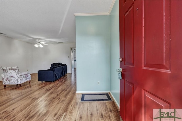 entryway featuring baseboards, ceiling fan, wood finished floors, crown molding, and a textured ceiling