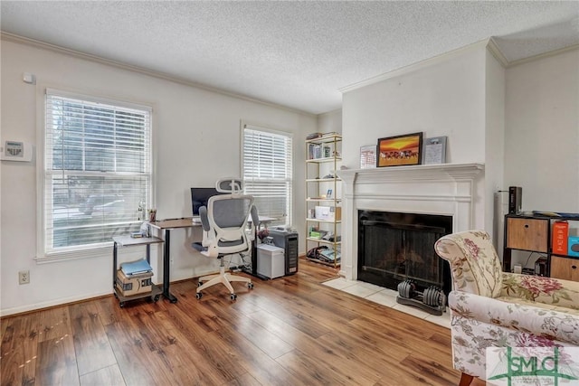 office area featuring a fireplace with flush hearth, a textured ceiling, ornamental molding, and wood finished floors