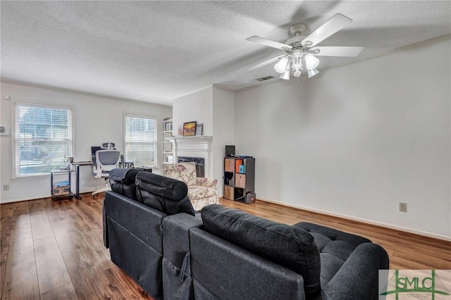 living room with a textured ceiling, dark wood-style flooring, a fireplace, and visible vents