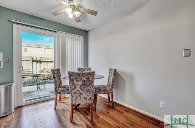 dining room featuring a textured ceiling, baseboards, and wood finished floors