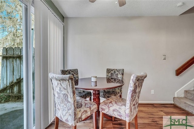 dining room featuring baseboards, a textured ceiling, stairway, and wood finished floors