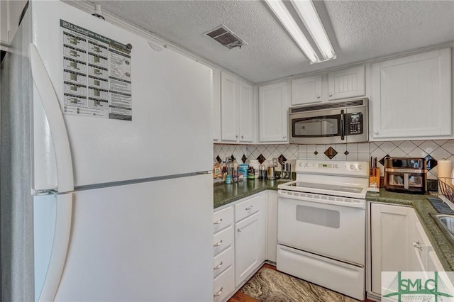 kitchen featuring white appliances, visible vents, decorative backsplash, and white cabinets