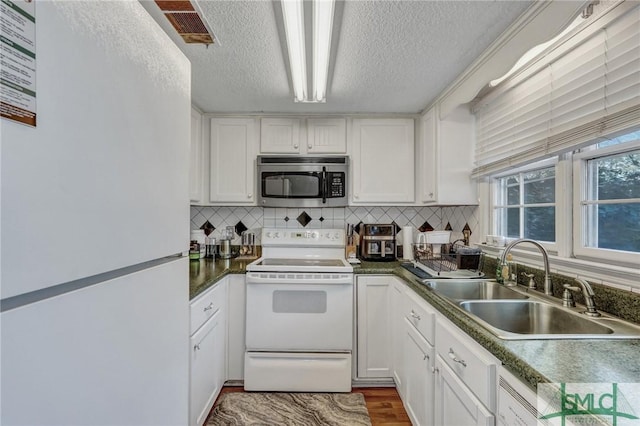 kitchen with white appliances, a sink, visible vents, and decorative backsplash