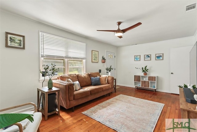 living area with a ceiling fan, visible vents, baseboards, and wood finished floors