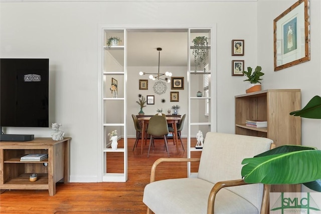 living area with baseboards, an inviting chandelier, and wood finished floors